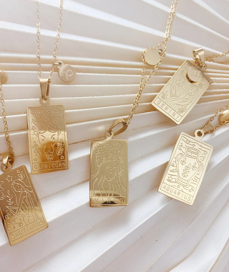 Gold tarot card pendants on a textured white surface