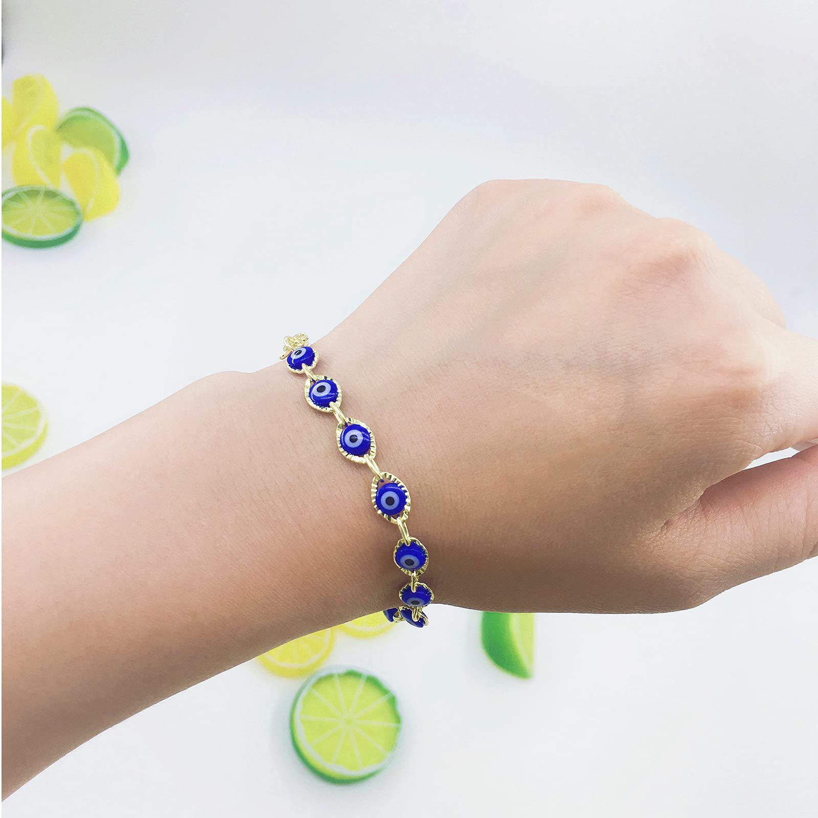 Hand wearing a blue evil eye beaded bracelet with a white background.