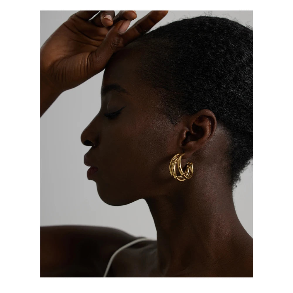 Profile of a person wearing gold hoop earrings with a neutral background