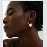 Close-up of a woman wearing gold hoop earrings with a blurred background