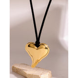 Gold heart-shaped pendant on a black cord against a neutral background