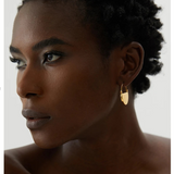 Woman wearing gold hoop earrings with a neutral background