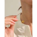 Gold necklace with a rose pendant being worn by a person.