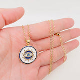 White enamel evil eye pendant necklace with gold chain and sparkling blue stones, designed for protection and daily wear.