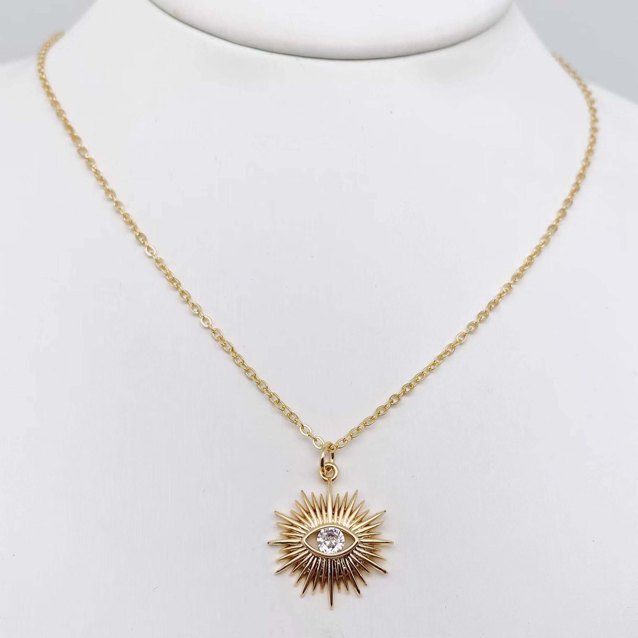 Protective evil eye sunburst pendant necklace for women with a shimmering cubic zirconia in a gold-plated setting.