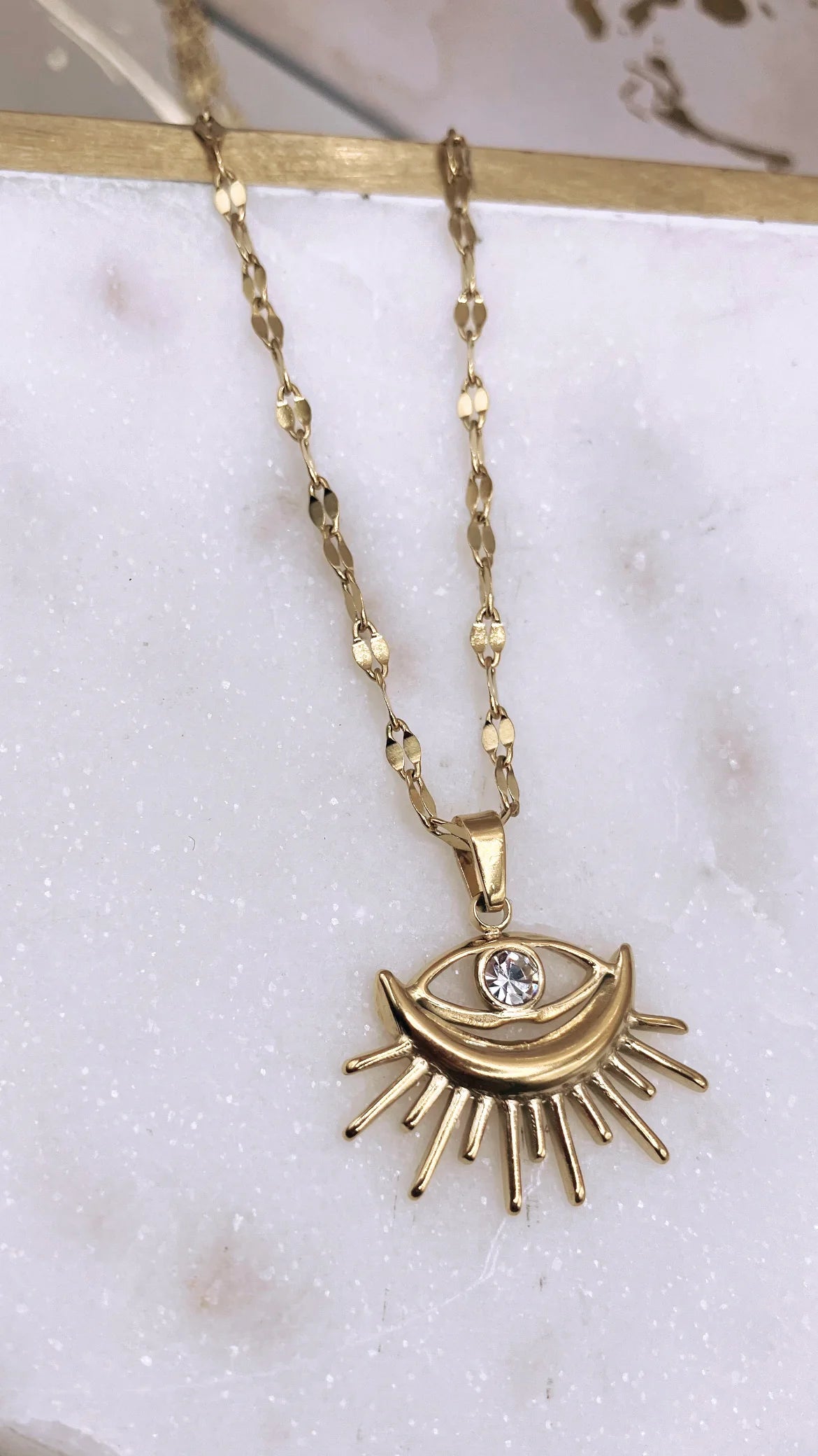 Stylish Gold-Plated Sunburst Evil Eye Pendant Necklace with rhinestone center, perfect for adding charm and protection to any outfit.