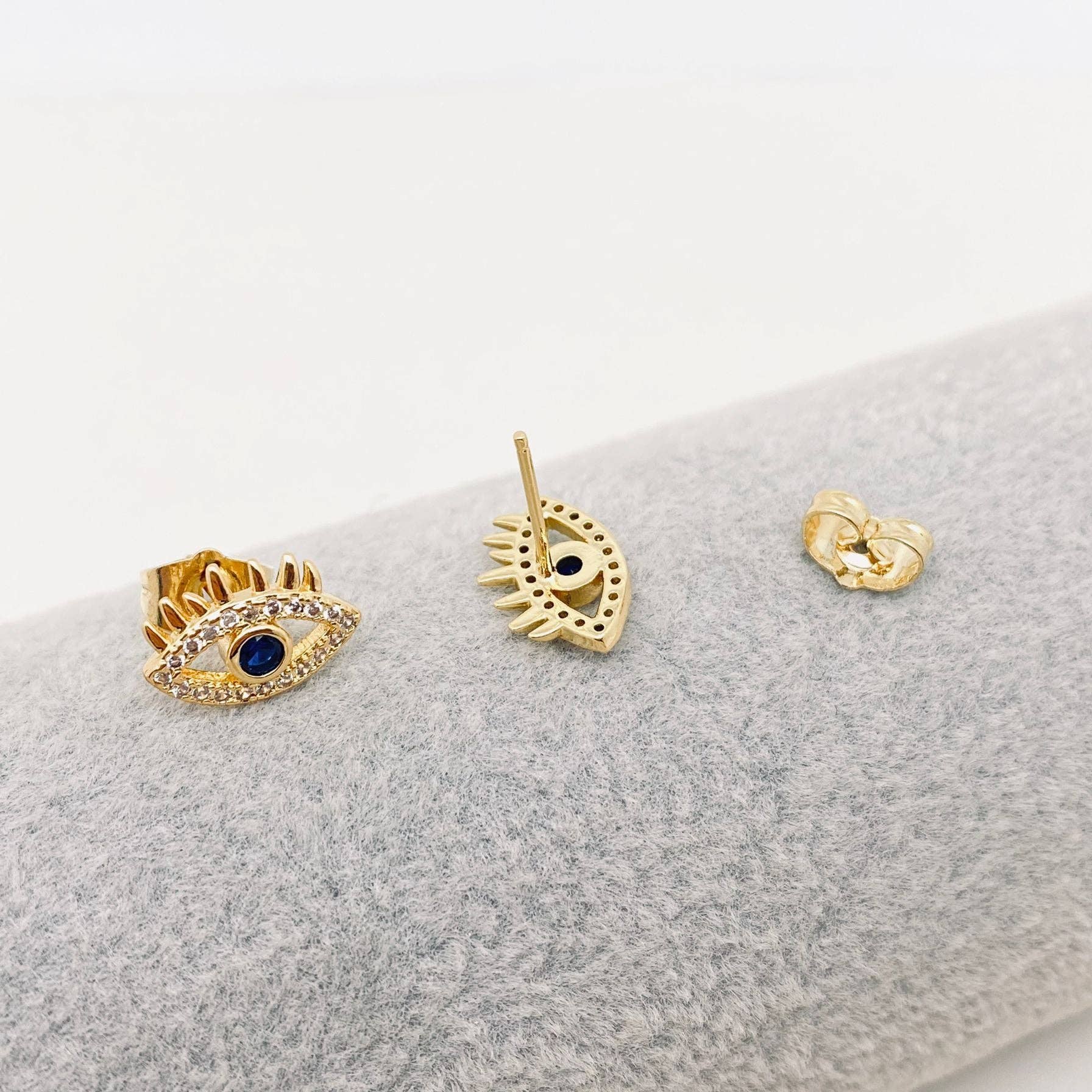 Elegant golden evil eye stud earrings with deep blue center and sparkling cubic zirconia, 18k gold plated on stainless steel, perfect for everyday wear.