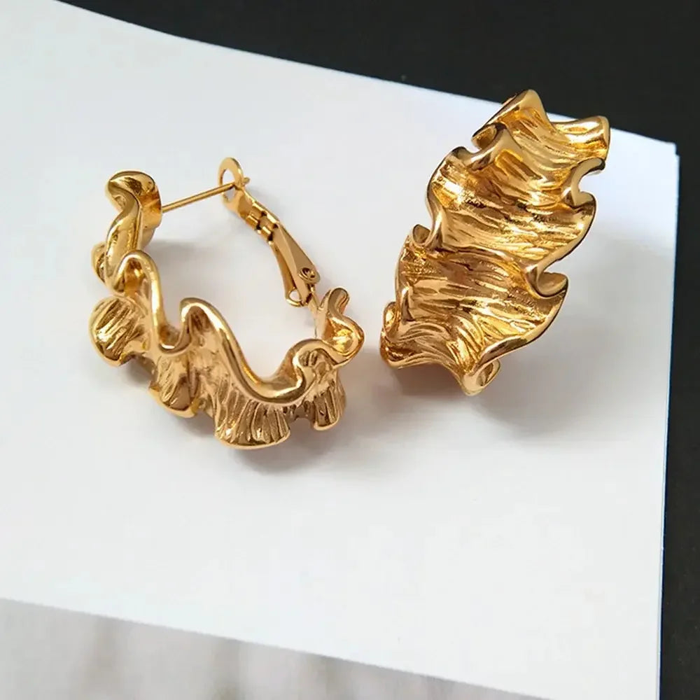 Modern gold ripple hoop earrings with fluid design, 18k gold plated for a bold and stylish statement piece.