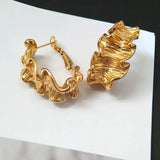 Modern gold ripple hoop earrings with fluid design, 18k gold plated for a bold and stylish statement piece.