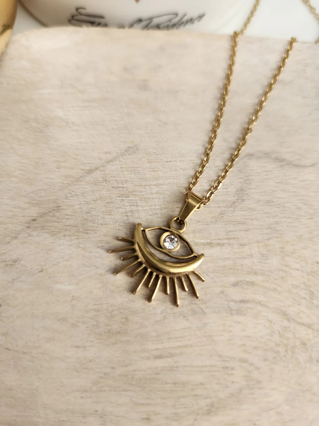 Chic Sunburst Evil Eye Pendant Necklace, gold-plated with a rhinestone center, perfect for protection and adding a stylish touch to any look.
