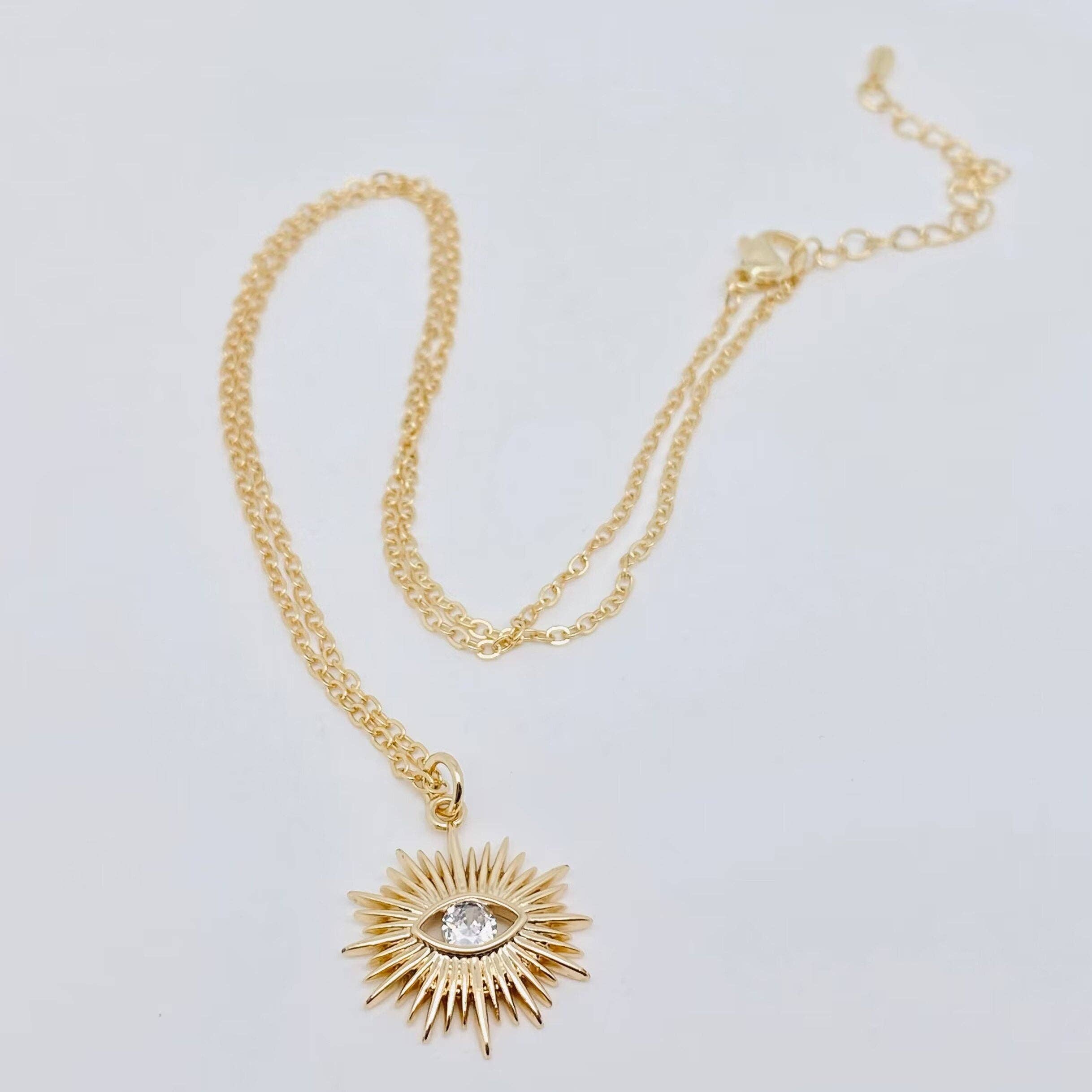 Gold-plated sunburst evil eye pendant necklace with cubic zirconia center, offering stylish protection and elegance for everyday wear.
