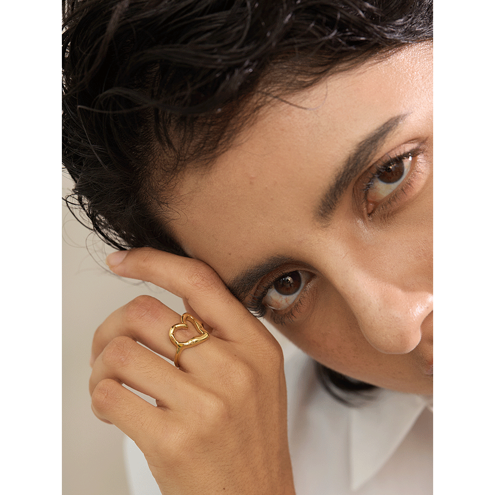 Close-up of a person wearing a gold ring with a heart design.