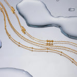 18K Gold Beaded Layered Necklace with three delicate chains and polished beads, designed to add depth and elegance to any outfit.