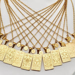 Gold zodiac necklaces with zodiac pendants on a white surface