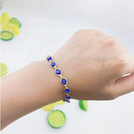 Hand wearing a blue evil eye beaded bracelet with a white background.