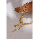 Gold chain bracelet with lock and key charms on a textured surface
