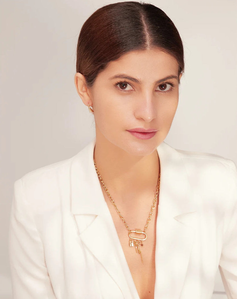 Woman wearing a white blazer and gold necklace against a light background