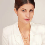 Woman wearing a white blazer and gold necklace against a light background