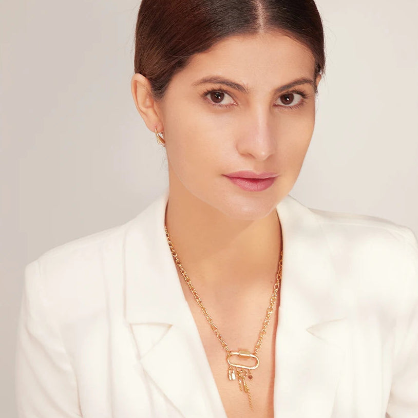 Woman wearing a white blazer and gold necklace against a light background