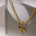 Gold chain necklace with lock and key charms on a light gray surface