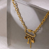 Gold chain necklace with lock and key charms on a light gray surface
