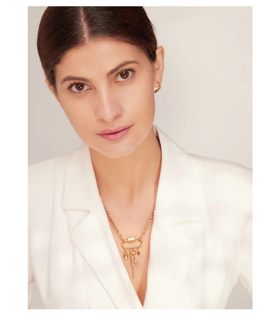 Woman wearing a gold necklace against a plain background