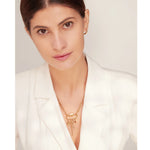 Woman wearing a gold necklace against a plain background