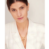 Woman wearing a gold necklace against a plain background