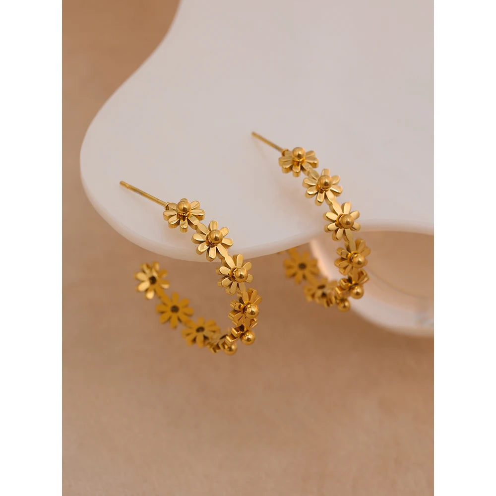 Gold floral hoop earrings on a neutral background