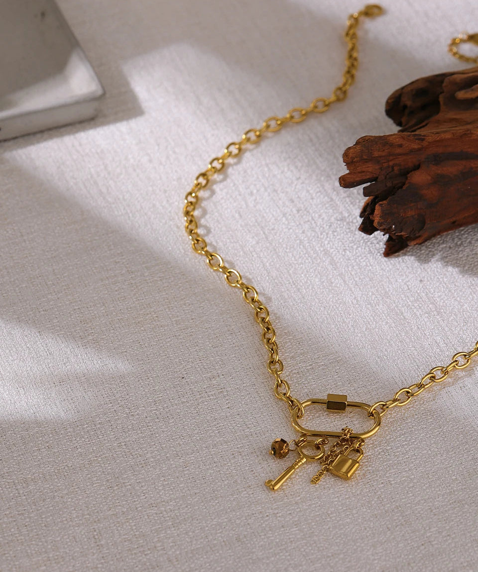 Gold necklace with key charms on a textured surface