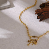 Gold necklace with key charms on a textured surface