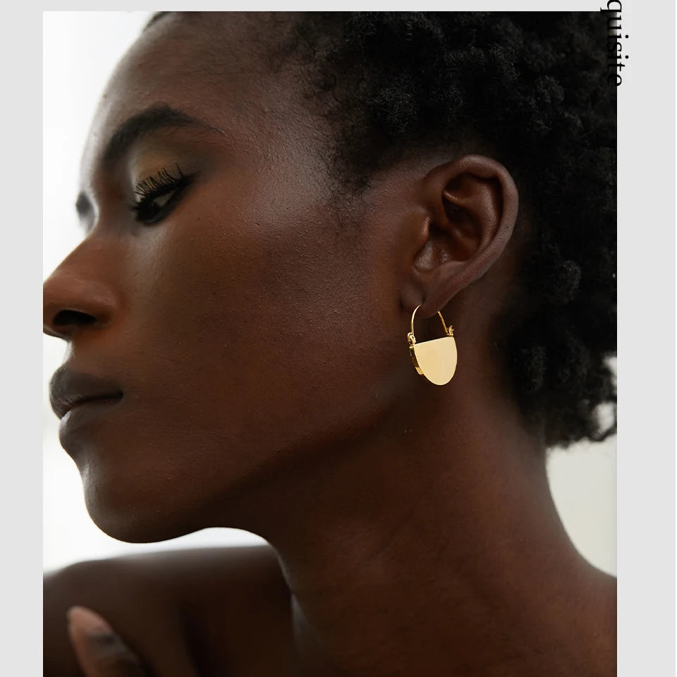Close-up of a woman wearing gold hoop earrings with a blurred background 