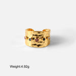 Gold ring with embedded gemstones on a light gray background