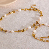 Gold chain necklace with pearls on a textured surface