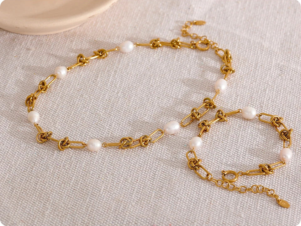 Gold chain necklace with pearls on a textured surface