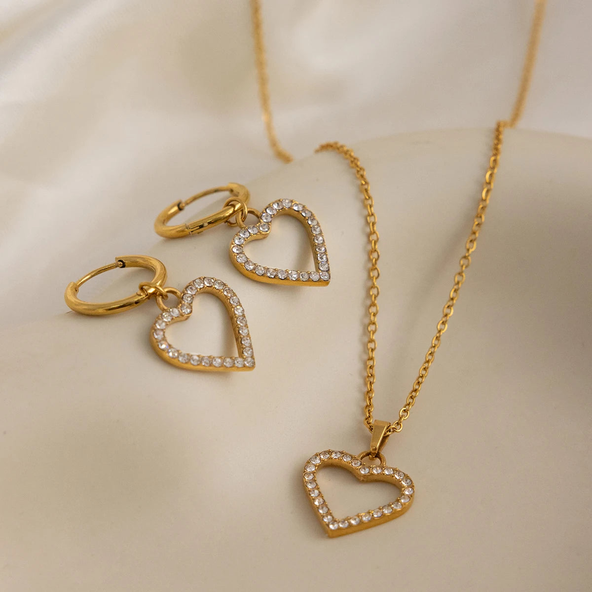 Gold heart-shaped jewelry set on a beige background