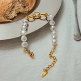 Pearl bracelet with gold chain on a light surface with bread and a fork in the background