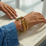Gold bracelets on a wrist with a blurred background