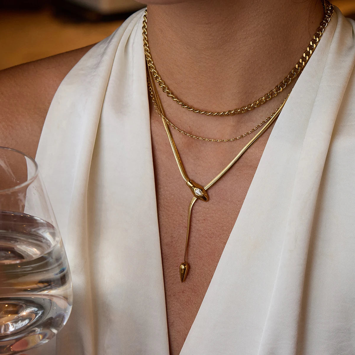 Gold necklaces on a person wearing a white outfit with a blurred background