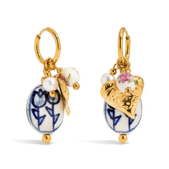 Pair of earrings with gold hooks, ceramic pendants, and pearls on a white background