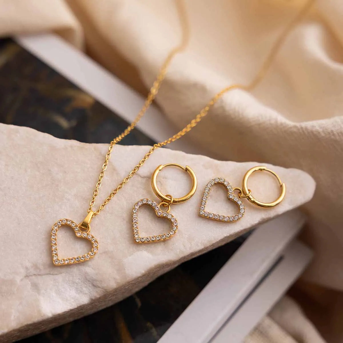 Gold heart-shaped jewelry set on a marble surface
