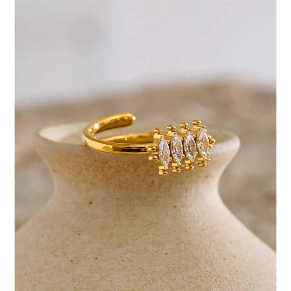 Gold ring with diamonds on a beige ceramic vase against a neutral background