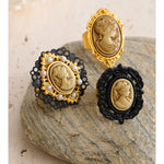 Pair of vintage-style earrings with cameo designs on a stone surface