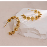 Gold floral hoop earrings on a white fabric background with 'HAPPY' branding.