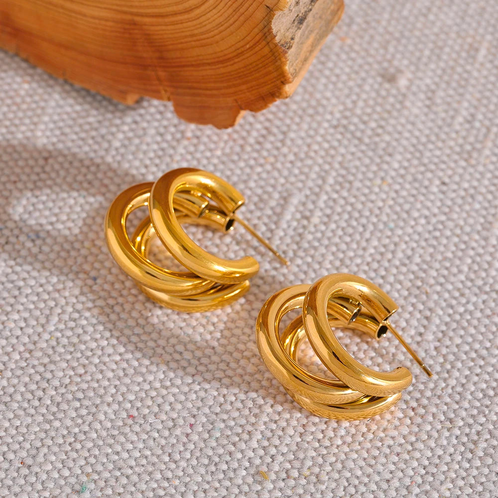 Gold hoop earrings on a textured surface with wooden background