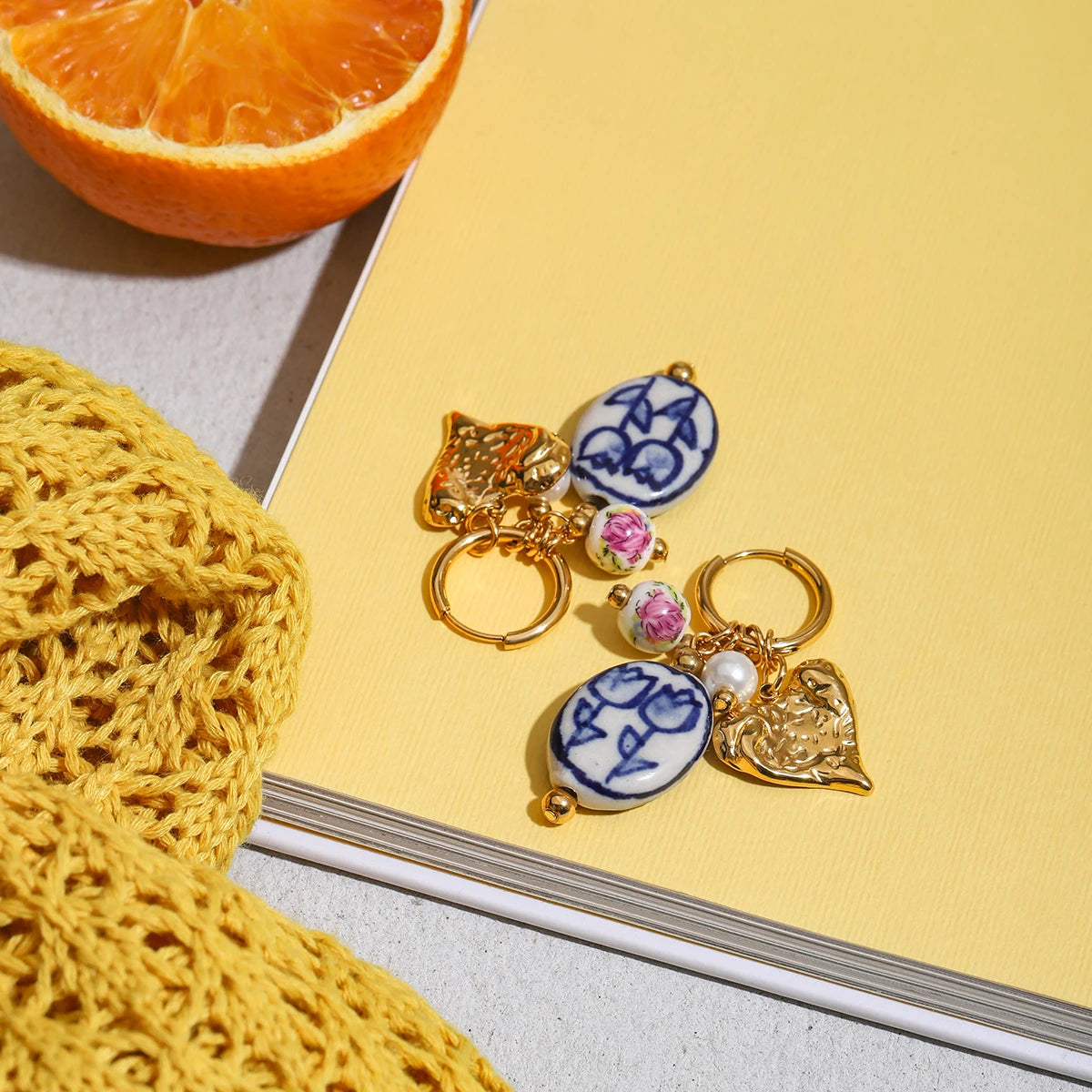 Decorative keychains with ceramic beads on a yellow surface next to a crocheted item and half an orange.