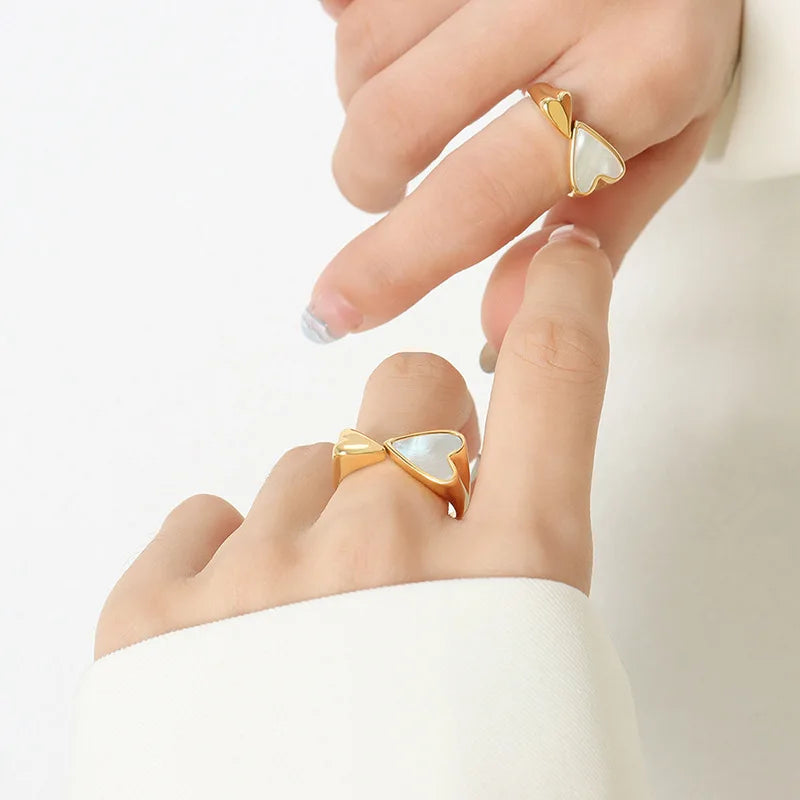Gold rings with white stones on a person's fingers against a light background