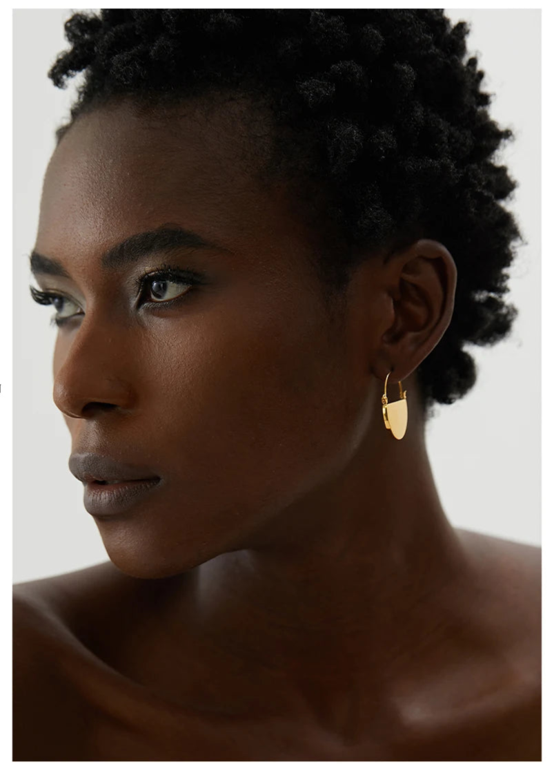 Woman wearing gold hoop earrings with a neutral background