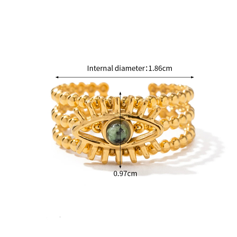 Gold ring with eye design and measurements on a white background