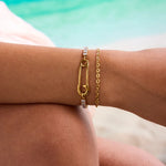 Gold bracelet with a unique design on a person's wrist against a blurred background